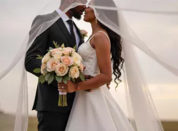 Bride and groom kissing under a veil on their wedding day