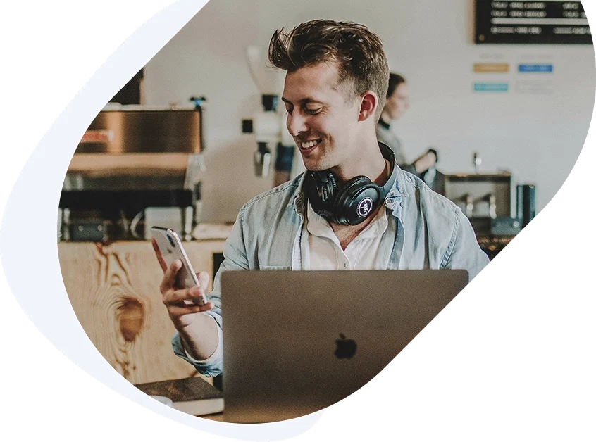 Smiling man at a cafe reading a phone notification about approval for a $300 dollar loan