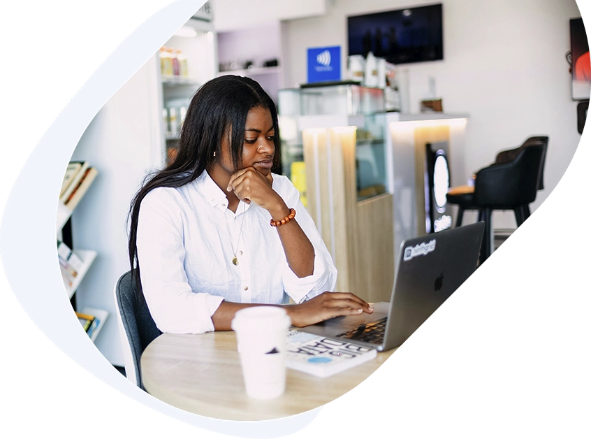 Focused woman reviewing terms of her $5,000 loan application on her laptop in a coffee shop