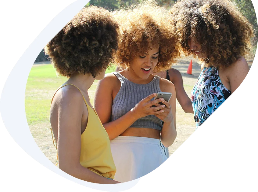 Young girls checking a phone together as they help their friend apply for a loan with pay stubs