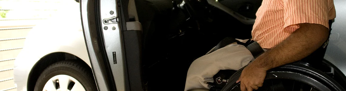 Man in a wheelchair by an open car door, representing everyday independence for disabled persons