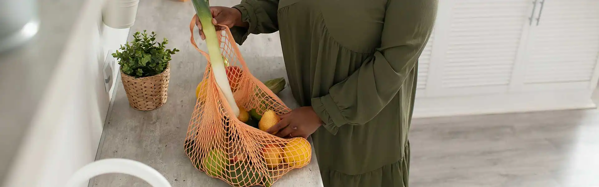 Woman unpacking groceries from a shopping bag while dealing with a tight budget
